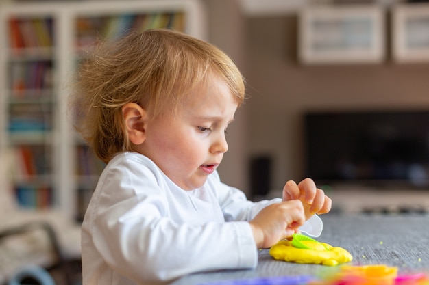 Niño sonriente moldes de plastilina de colores en la mesa