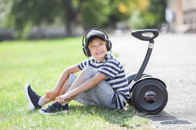 Niño sonriente montando segway. Juventud activa. Chico lindo al aire libre con rover eléctrico.