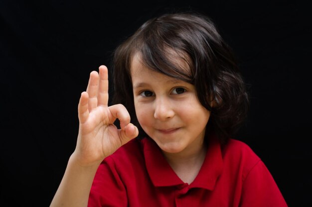 Foto niño sonriente mostrando una señal de mano o un gesto de mano