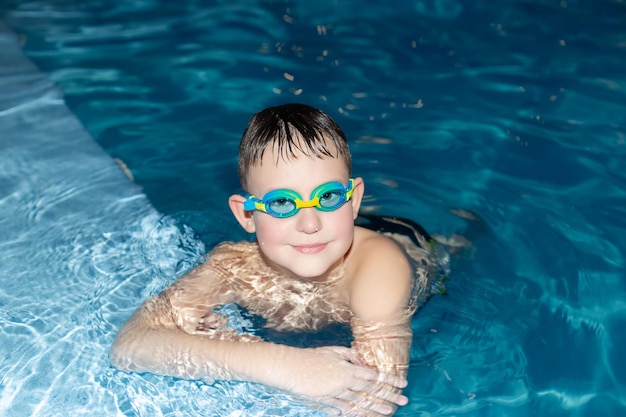 Un niño sonriente nada en la piscina Deportes y recreación Actividades de ocio y estilo de vida
