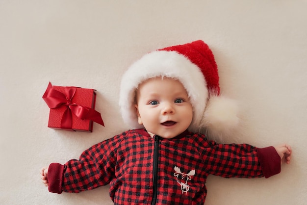 Niño sonriente de Navidad con sombrero de santa con regalos.