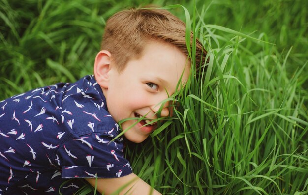 Niño sonriente niño con fondo de hierba Niño lindo disfrutando en el campo Unidad con la naturaleza