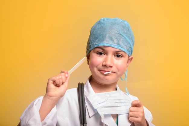 Niño sonriente niño médico sobre fondo amarillo Doc masculino en bata médica blanca Concepto de medicina sanitaria Concepto de maqueta de espacio de copia