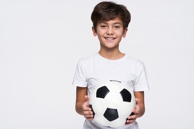 Foto niño sonriente con pelota de futbol