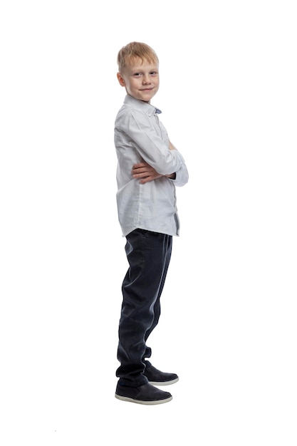 Foto niño sonriente está de pie un tipo con una camisa blanca y pantalones oscuros altura completa aislado sobre fondo blanco vertical