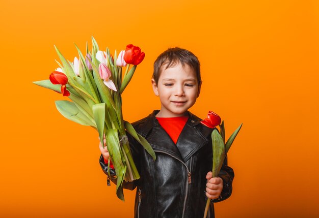 Niño sonriente con ramo de flores de primavera de tulipanes aislado en amarillo