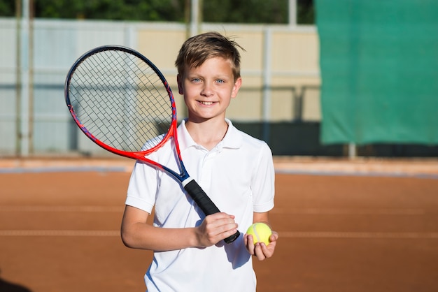 Foto niño sonriente con raqueta de tenis