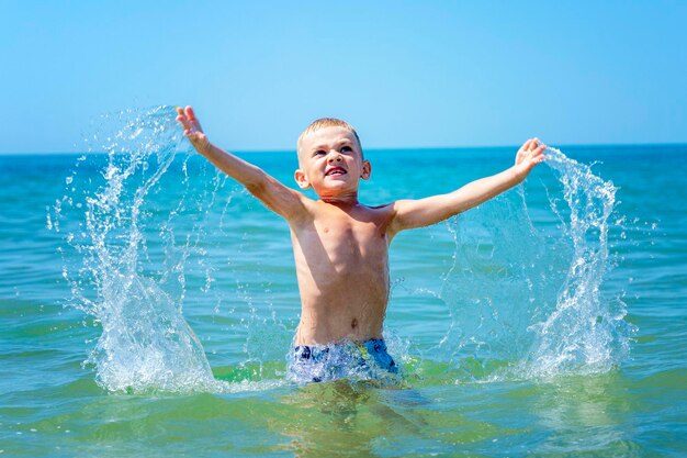 Un niño sonriente salta del mar en un día soleado Descanse en libertad y viaje