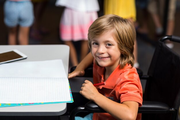 Niño sonriente en silla de ruedas por mesa