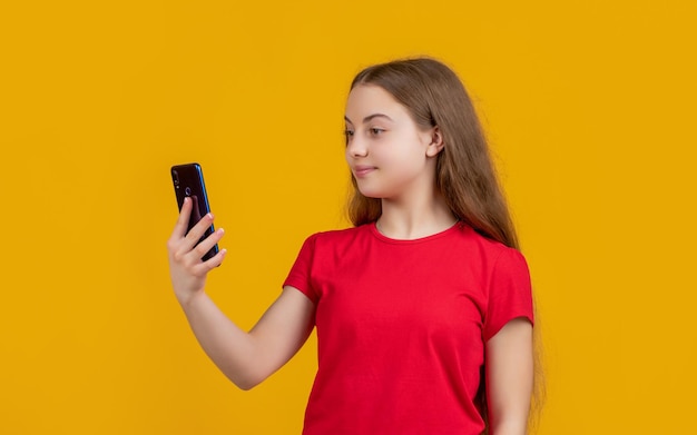 Niño sonriente con smartphone sobre fondo amarillo