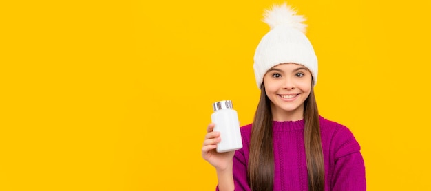 Niño sonriente en sombrero de invierno con tarro de pastillas suplemento alimenticio jovencita con productos de pastillas naturales