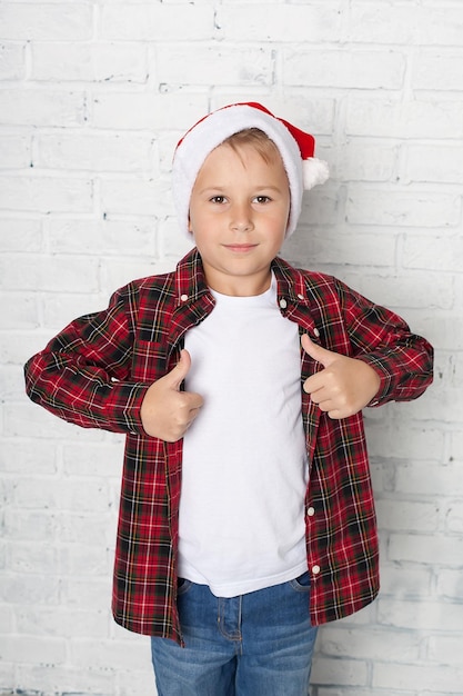 Niño sonriente en el sombrero de Papá Noel con caja de regalo aislado en blanco