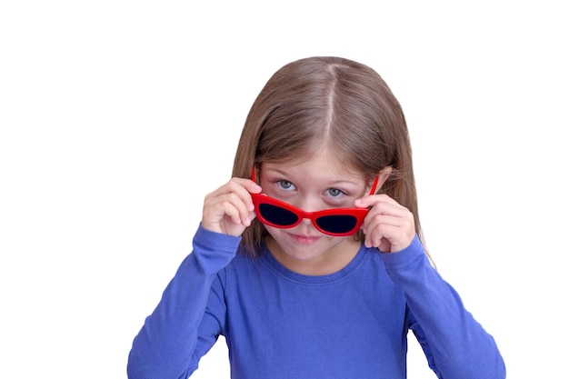 Niño sonriente sosteniendo gafas de sol rojas sobre los ojos