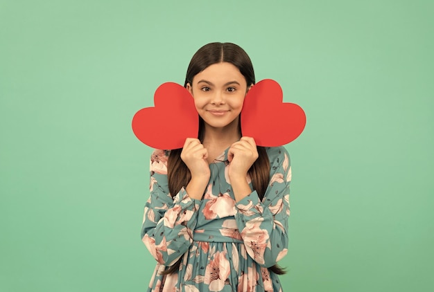 Niño sonriente sostiene el símbolo del corazón rojo del amor por el amor del día de san valentín