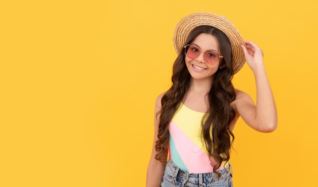 Niño sonriente usa sombrero de paja y gafas. niña alegre sobre fondo amarillo.