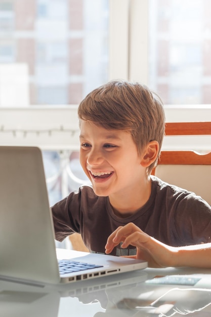 Niño sonriente usando una computadora portátil en la mesa