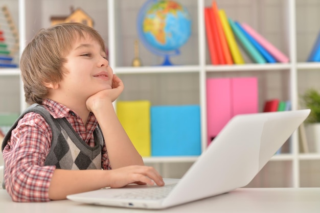 Niño sonriente usando laptop en casa