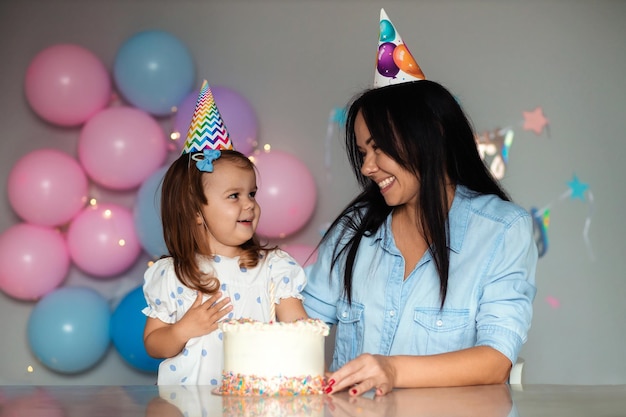 El niño sopla las velas del pastel. Madre e hija celebran un cumpleaños.