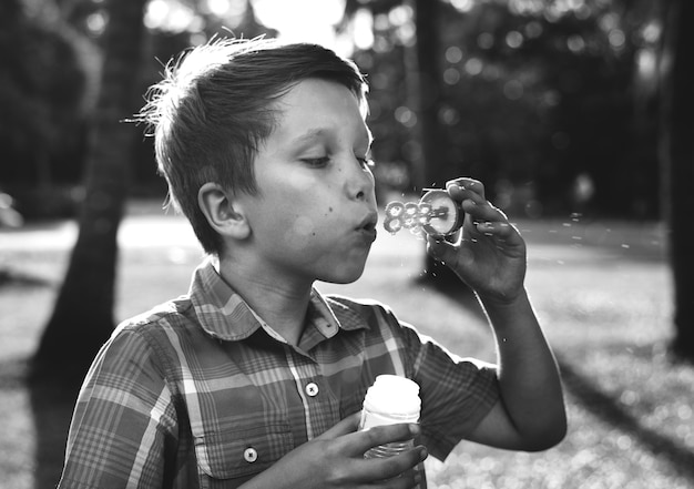 Niño soplando pompas de jabón en el parque