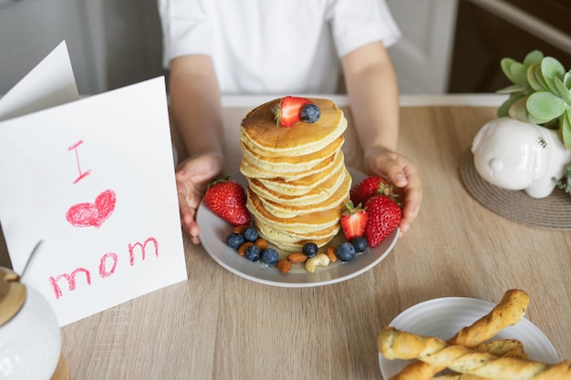 El niño sorprende a su madre el día de la madre Panqueques para el desayuno y una tarjeta de I love mom