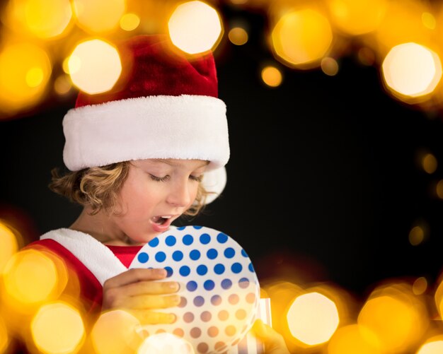 Niño sorprendido con caja de regalo de Navidad. niño feliz divirtiéndose en casa. Concepto de vacaciones de Navidad