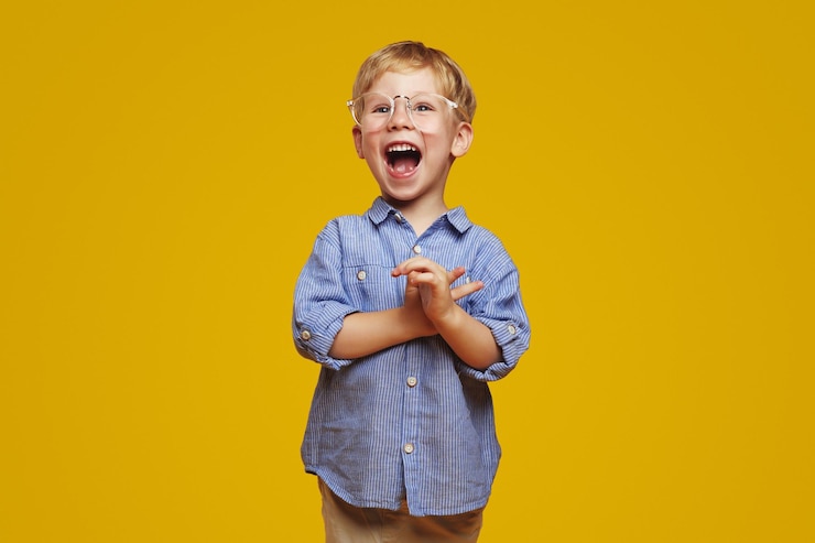 Foto niño sorprendido con camisa azul a rayas y gafas elegantes aplaudiendo y gritando