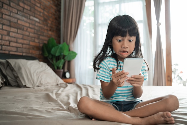 Niño sorprendido mientras mira su teléfono móvil