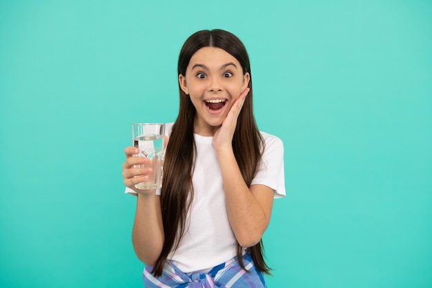 Niño sorprendido que va a beber un vaso de agua para mantenerse hidratado y mantener el equilibrio diario del agua en la salud corporal