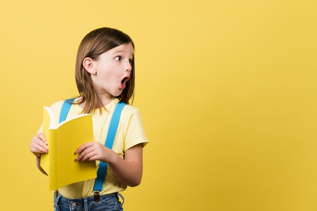 Niño sorprendido sosteniendo un libro y mirando el espacio de la copia