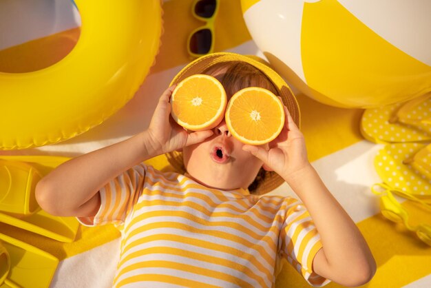 Niño sorprendido sosteniendo rodajas de fruta naranja como gafas de sol