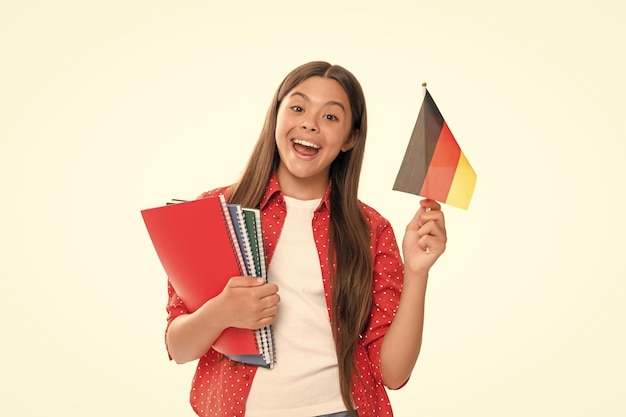 Niño sorprendido sostiene la bandera alemana y el cuaderno escolar para estudiar aislado en el idioma alemán blanco