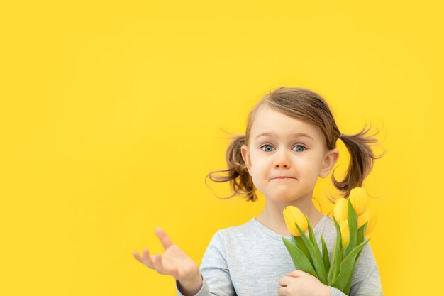 Niño sorprendido sostiene ramo de tulipanes amarillos