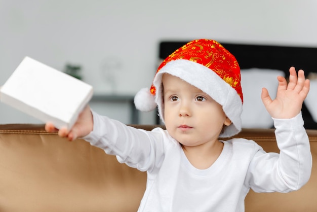 Un niño sorprendido sostiene un regalo de navidad en su mano.