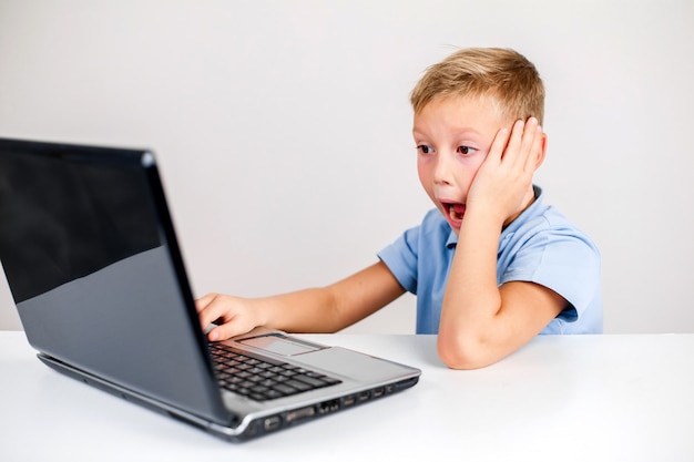 Niño sorprendido usando laptop con la boca abierta