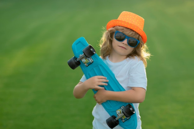 Niño sostenga patineta en un día soleado en el parque al aire libre retrato de niño pequeño skater ridin