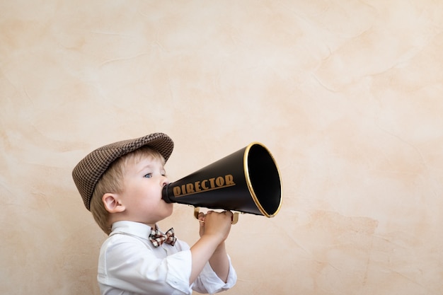 Niño sosteniendo el altavoz. Niño gritando por megáfono vintage. Concepto de noticias empresariales