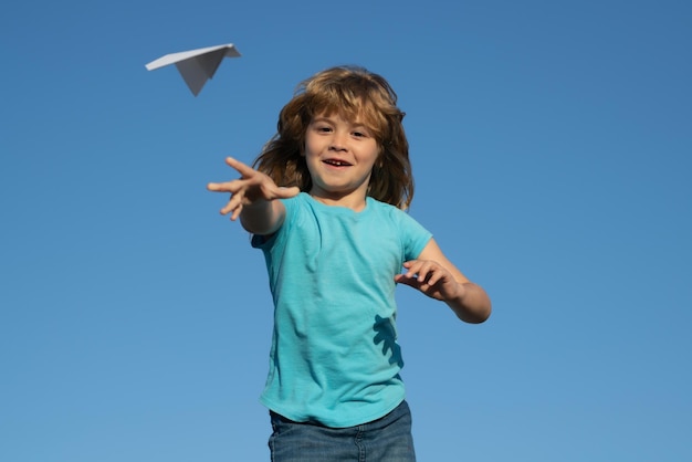 Niño sosteniendo un avión de papel al aire libre Niño feliz jugando con un avión de papel contra el cielo Un niño con un avión de papel