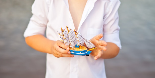 Niño sosteniendo un barco de juguete, modelo del barco.