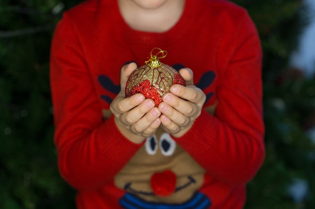 Foto niño sosteniendo una bola de decoración navideña