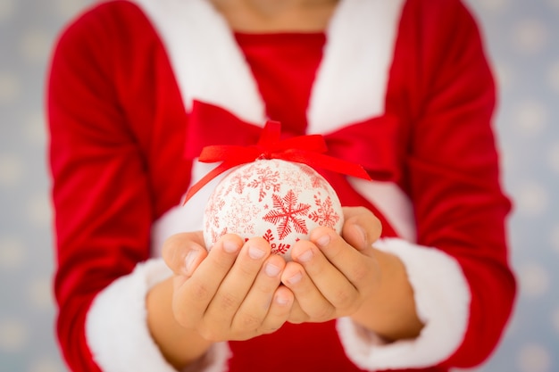 Niño sosteniendo la bola de Navidad. Concepto de vacaciones de Navidad