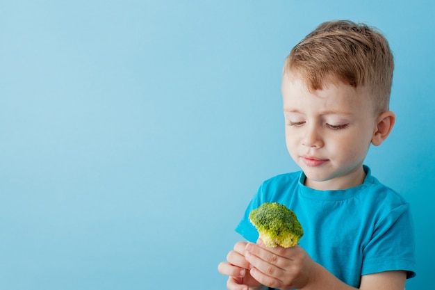 Niño sosteniendo brócoli en sus manos en azul