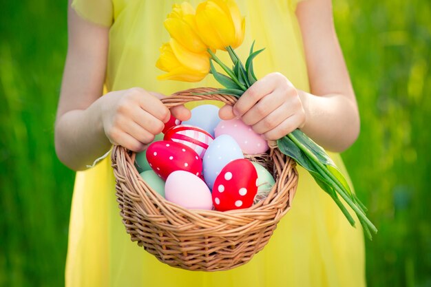 Niño sosteniendo una canasta con huevos de Pascua al aire libre en el parque de primavera