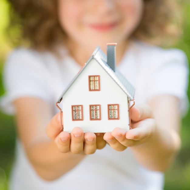 Foto niño sosteniendo casa en manos al aire libre