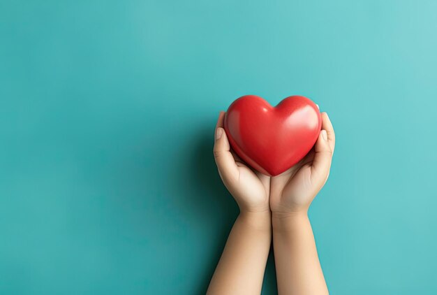 un niño sosteniendo un corazón rojo en sus manos en fondo turquesa en el estilo minimalista