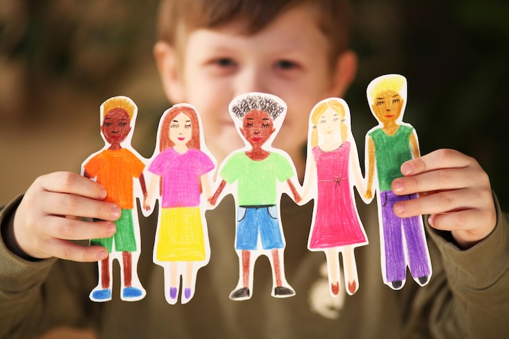 Foto niño sosteniendo guirnaldas caseras de papel de personas de diferentes razas