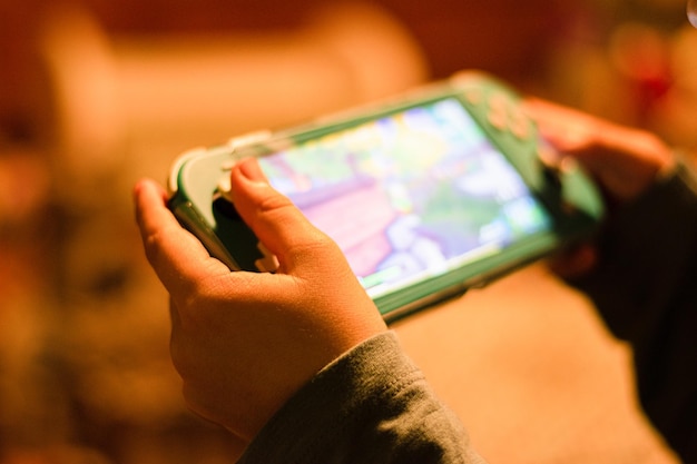 Un niño sosteniendo y jugando una consola de videojuegos.
