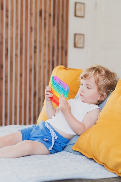 Niño sosteniendo juguetes anti estrés sensorial pop it en su mano Niño pequeño plaing con juguete sensorial fidget