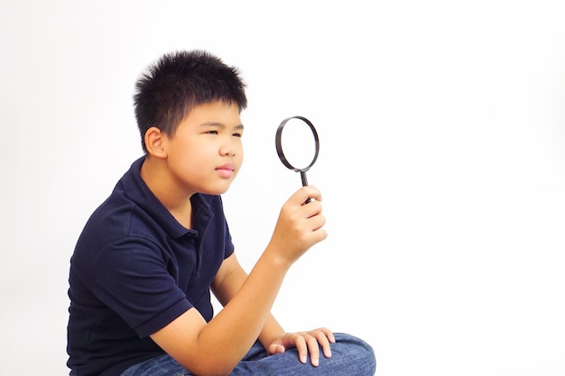 Niño sosteniendo una lupa sobre fondo blanco Investigación de conocimientos y concepto de exploración