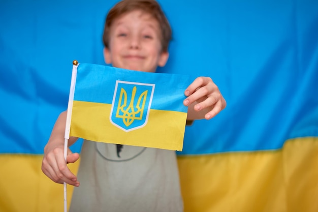 Niño sosteniendo en las manos la bandera ucraniana sobre fondo amarillo azul Guerra de Rusia contra Ucrania