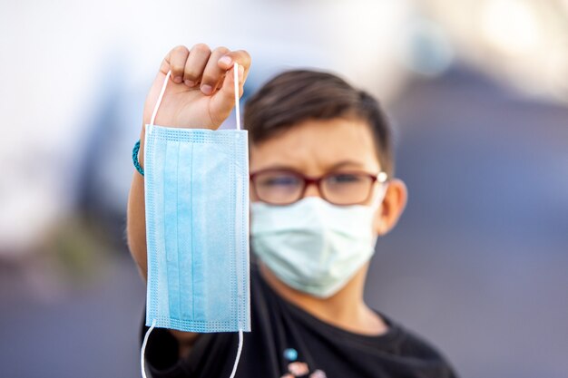 Niño sosteniendo una máscara médica, primer plano. Detén el coronavirus. Enfoque selectivo